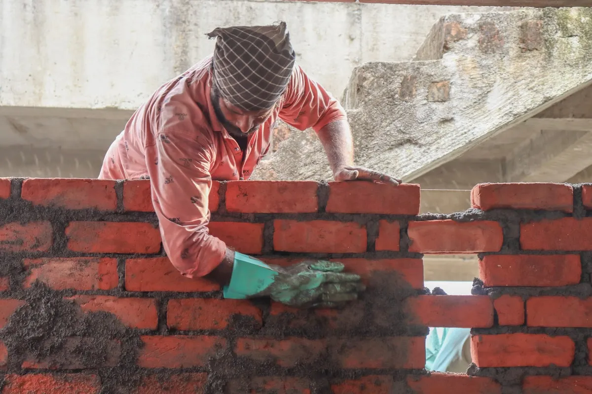 A mason laying brick to a taut string line